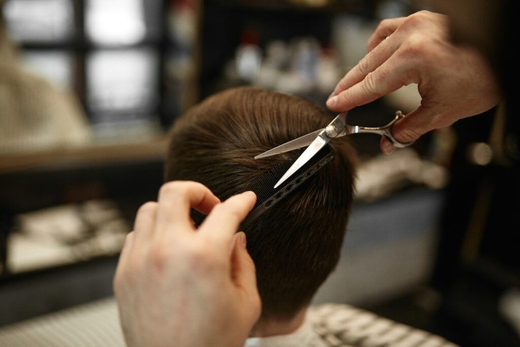 a person cutting another persons hair with a pair of scissors